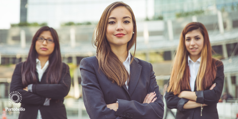 Three women with arms folded wearing suits looking at the camera