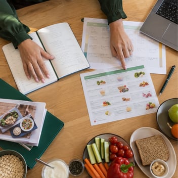 Dietitian reviewing a food diary and personalised meal plan at a desk