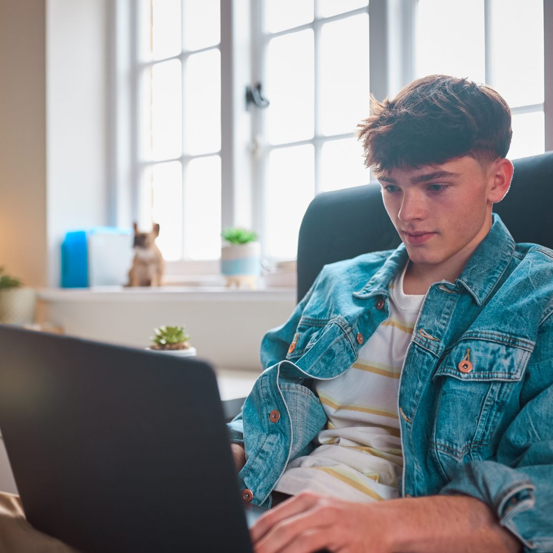 A teenage boy works on his laptop