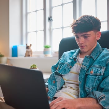 A teenage boy works on his laptop