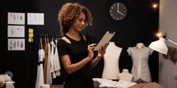 Woman looking and smiling at an electronic tablet in a fashion studio