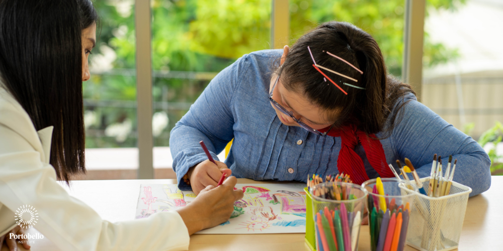 woman sitting at a table with a child colouring a picture
