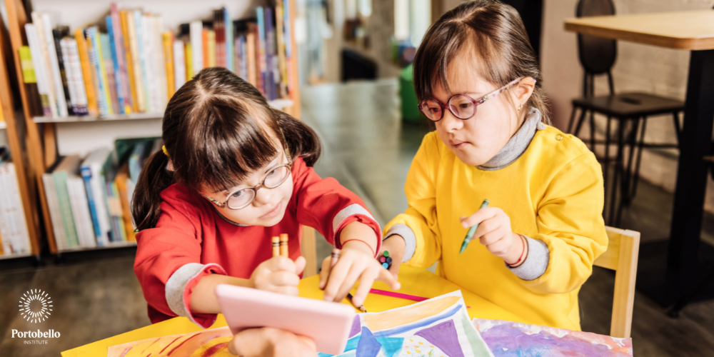 two little girls looking at an electronic tablet inclusive education