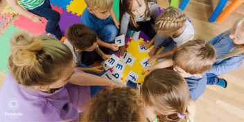 Preschool teacher with children around a table using cut out letters