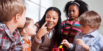 preschool teacher smiling and working with small children