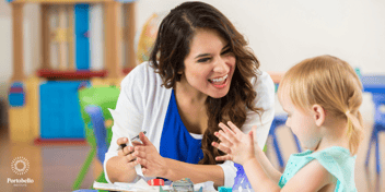Preschool teacher laughing and smiling with a young child