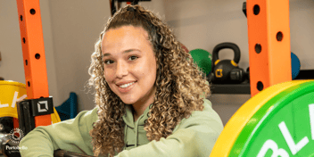 Girl surrounded by weights in a gym smiling