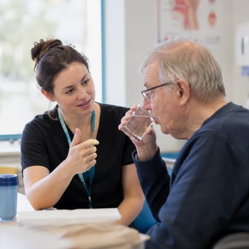 A speech and language therapist supports a man with drinking and swallowing
