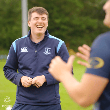 A man on a grassy sports field smiling 