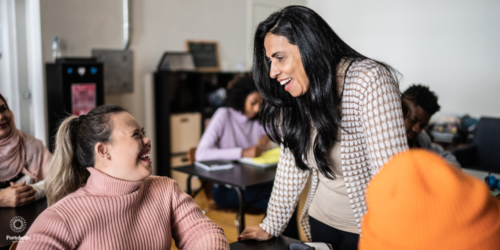 special needs assistant working in a classroom smiling and laughing with a student