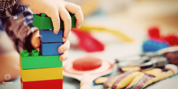 A close up of a child's hands on colourful plastic blocks