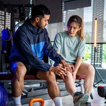 Sports therapist helps woman at the gym