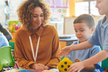 preschool children and a teacher sitting at a table playing