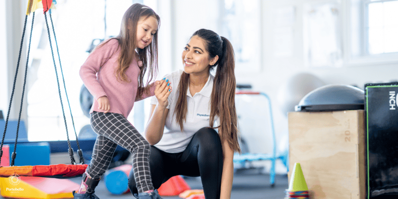 An occupational therapist holding a child's hand while she takes a step