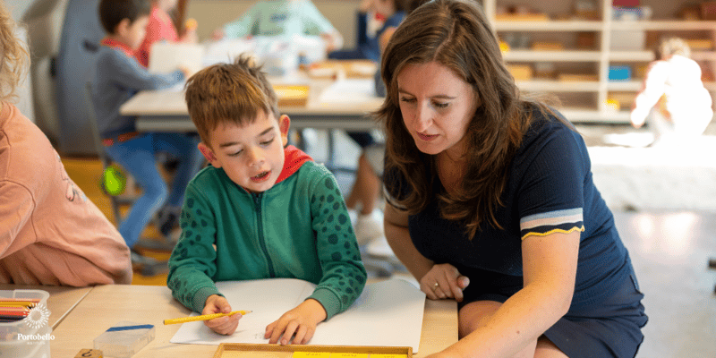 a teacher working with a young child at a desk