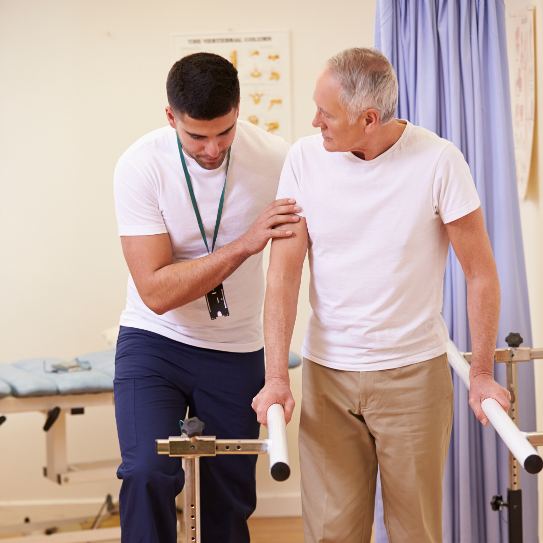 An occupational therapist supports a man walking in a clinical setting