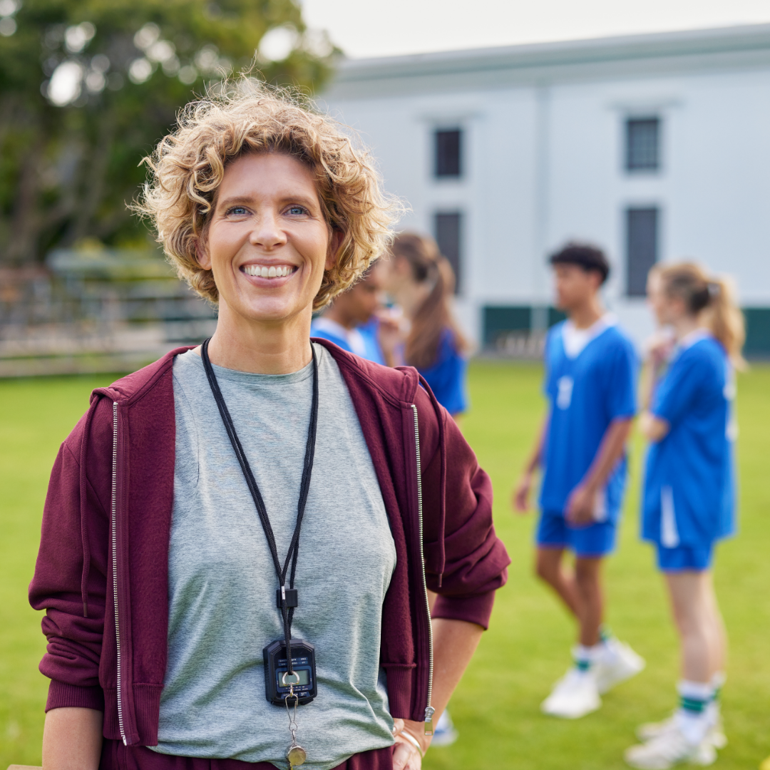 Female sports coach stands proudly with her young football team
