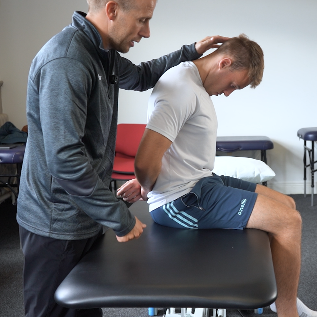 man sitting on bed doing exercise to improve mobility with a physiotherapist