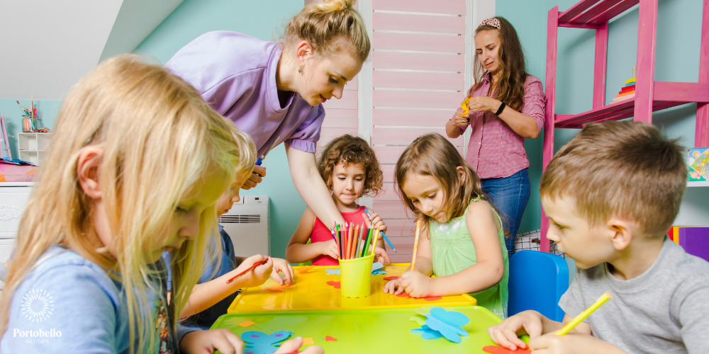 Two preschool teachers with children at a colourful table