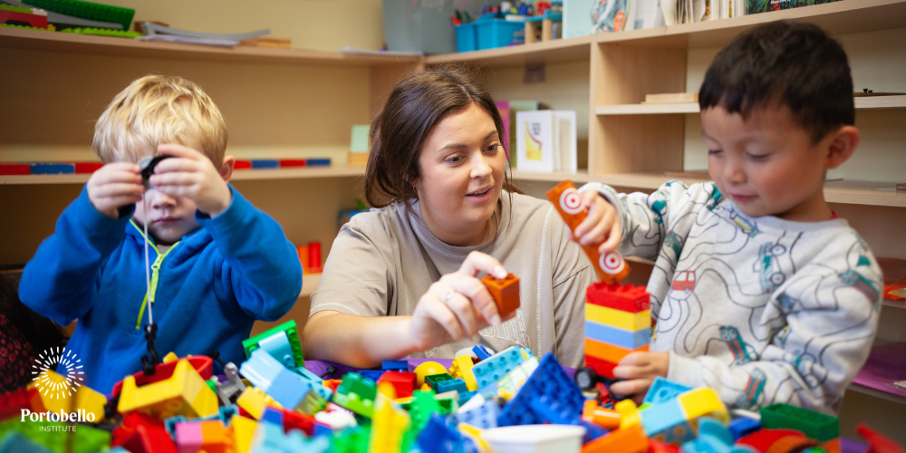 early childhood educator working with two children and colourful blocks